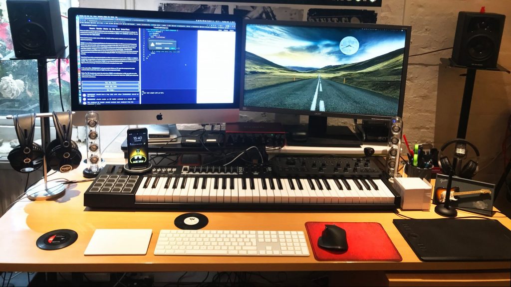 A computer workstation with two screens and a midi controller